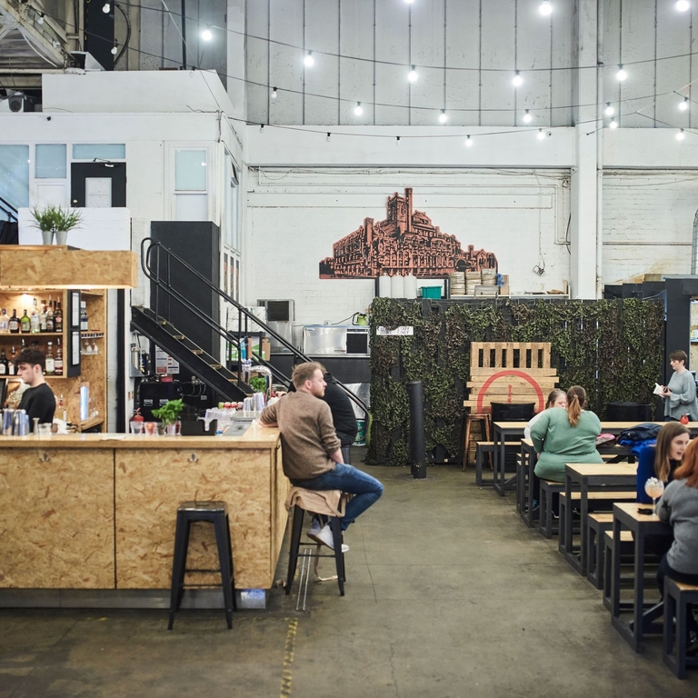 Indoor food court with wooden food stalls and picnic benches