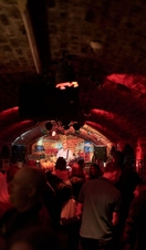 Brick tunnel-shaped room with music act on stage