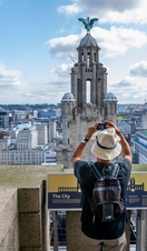 Gentleman photographing the tower in the skyline from the roof of the Royal Liver Building 360, Merseyside. Silver winner of the Small Visitor Attraction of the Year in the VisitEngland Awards for Excellence 2022