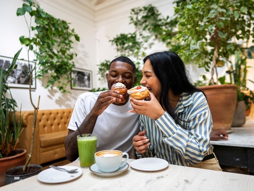 A man and a woman have cake and drinks in a cafe