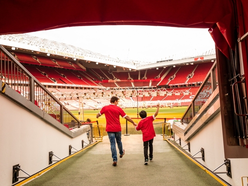 A man and boy in stadium tunnel looking out to pitch
