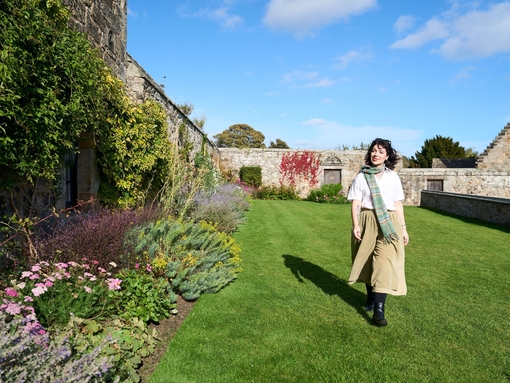 A woman walking through the gardens of a castle