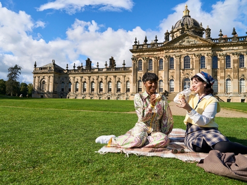 Two women enjoy scone with jam and cream in the garden of a heritage property