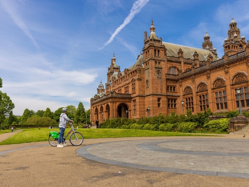 A cyclist parked out the front of an ornate Art Gallery and Museum.