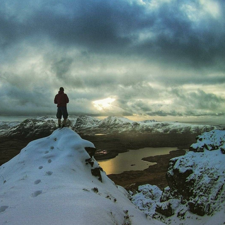 Personne au sommet d'une montagne enneigée regardant le paysage