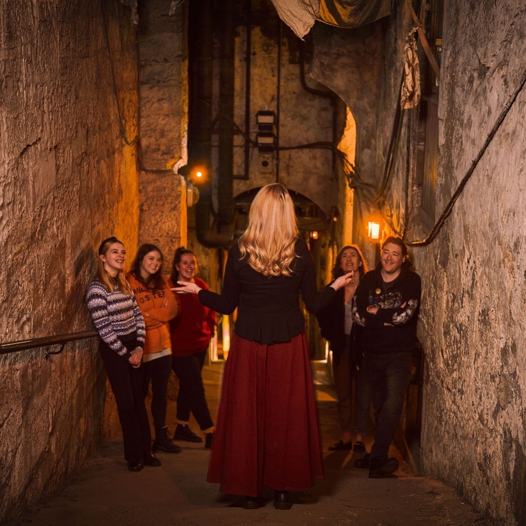 A tour guide leading a tour through the Real Mary King's Close in Edinburgh, Scotland