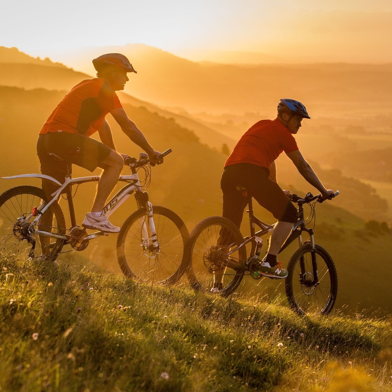 Dos hombres en bicicleta de montaña pedaleando en Devil's Dyke al amanecer