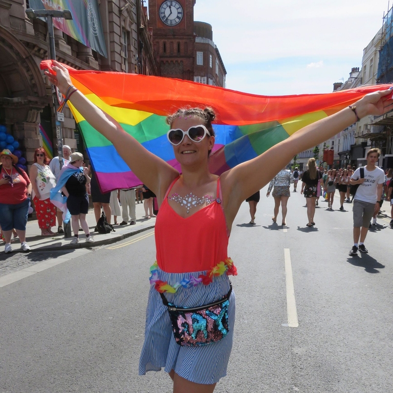 Mujer ondeando la bandera arco iris durante un acto del Orgullo