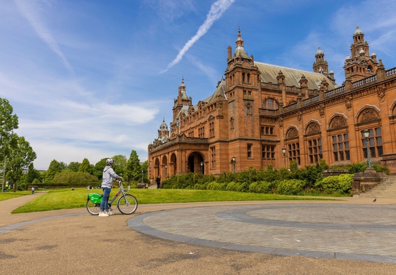 A cyclist parked out the front of an ornate Art Gallery and Museum.