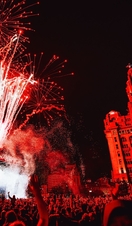 Crowds of people watching a band at a music festival as fireworks explode, in front of the Liver Building.
