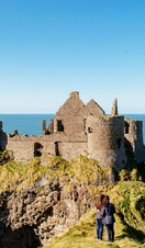 People looking at a historic stony castle from a hill
