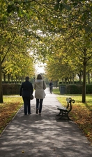 Two ladies walking through a tree lined path in Rowntree Park, York.