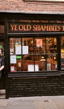 Hombre de pie frente a la taberna Ye Old Shambles