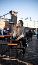 A woman sitting on a bench smiling and holding a lollipop