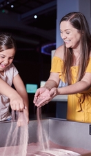 Mother and daughter play with sand at a science museum