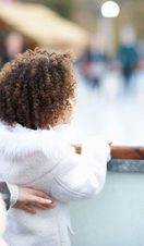 Rear view of mother and daughter watching people ice skating on ice rink
