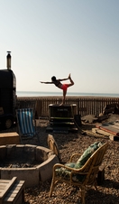 Woman holds a yoga pose at the Beach Box Sauna in Brighton