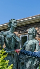 A girl putting flowers into the hands of a statue