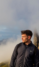 Couple standing near basalt pinnacles, watching mist