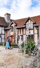 Couple walking around the exterior of Shakespeare's Birthplace, Stratford-upon-Avon, Warwickshire, England