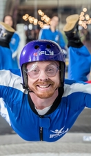 A person riding the iFLY Indoor Skydiving experience with a crowd of people watching behind