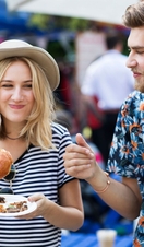 Couple eating burgers at food market.