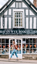 Young woman wearing backpack walks past bookshop