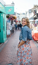 Smiling woman in denim jacket standing between shops