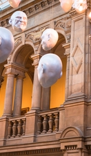 Two men looking at installation of suspended head sculptures