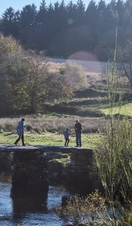 People walking on stone bridge across river