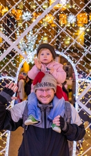 Man with young girl on his shoulders in front of lights