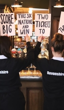 Two female staff from Devonshire Balham Public House holding signs for free tickets to Six Nations Rugby, Twickenham