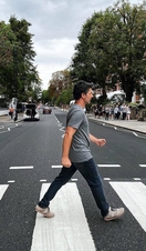 A man crossing the road outside of Abbey Road Studios, a recreation of the famous album cover from The Beatles