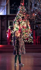 A girl looking at a hanging ornament in front of a decorated christmas tree at Bamburgh Castle's Christmas Kingdom