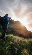 Man walking up hillside as the sun goes down