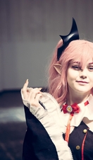 A female cosplayer dressed as a Japanese Anime character with colourful wig and make up at a comic con event