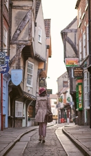 Mujer con sombrero rosa caminando por una calle estrecha