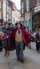A costumed guide in a wizard outfit walking through the street, part of The Wizard Walk of York, North Yorkshire