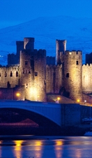 A castle lit up at night in winter snow near harbour