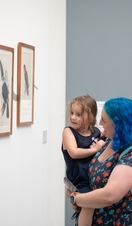 A woman carrying a child, looking at artworks in the Ruskin Collection at the Millennium Gallery in Sheffield