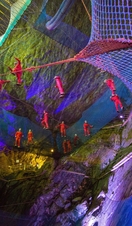 People in helmets and red jumpsuits at netting trampolines