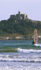 A person windsurfing off the coast of the castle on St Michael's Mount, Cornwall