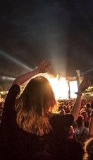 Woman swaying arms in the air whilst watching performance
