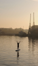 A person paddleboarding in the middle of Bristol's harbourside