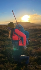 Female hiker with a backpack and walking poles, hiking through the countryside of Kilder in Northumberland at sunrise