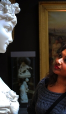 A woman looking at a sculpture on a pedestal in an art gallery