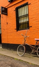 Bicycle parked outside jewellery boutique with orange painted wall in the Hidden Lane, Glasgow.