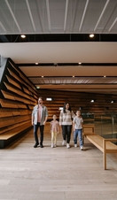 A man, a woman and two girls walking inside a modern museum.