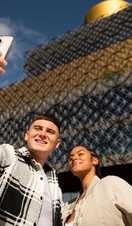 People posing for selfie in front of the Birmingham Library