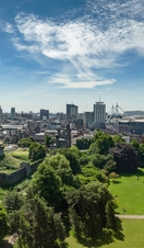 View of Bute Park, Cardiff from above, with green trees in the foreground and blue skies